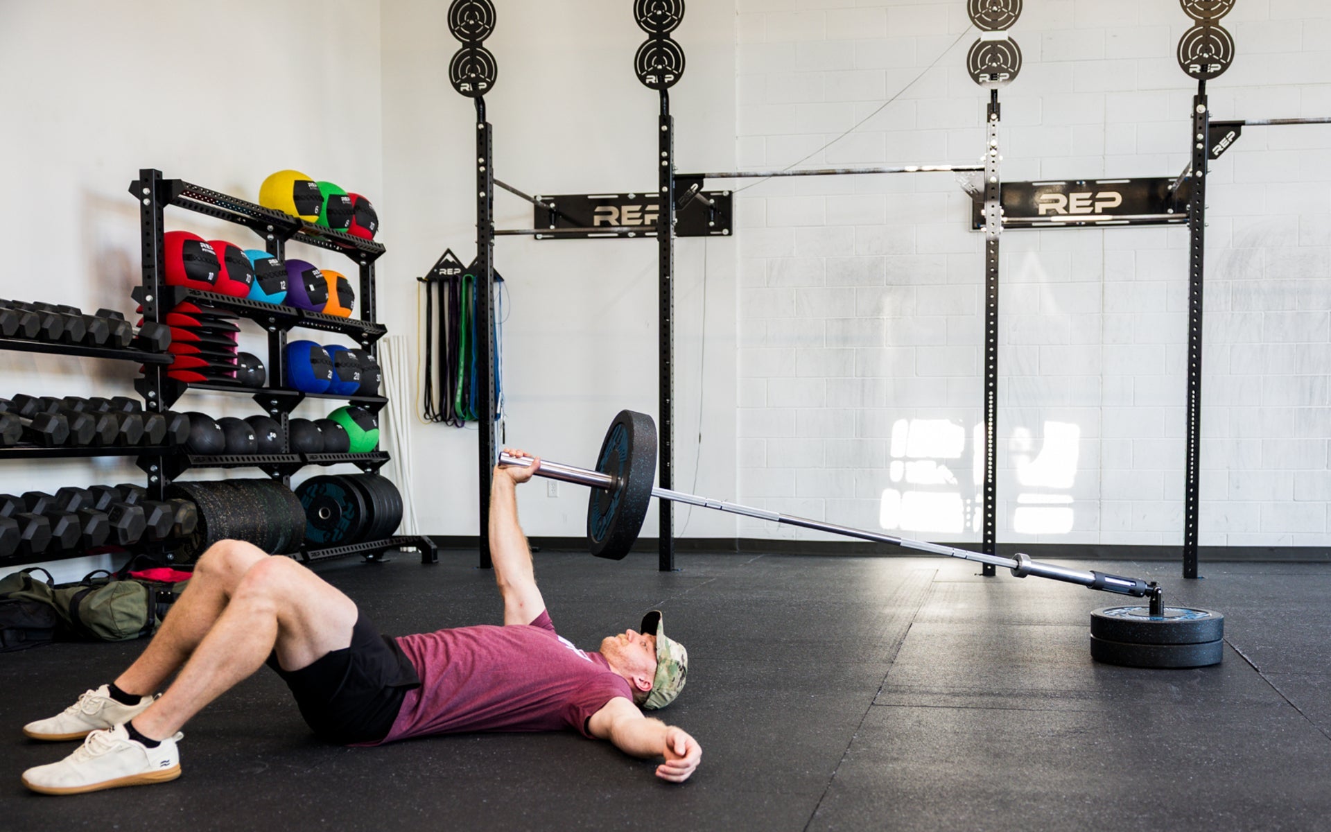 An athlete laying down performing presses with the Free Standing REP® x Kleva Built® Adroit Landmine